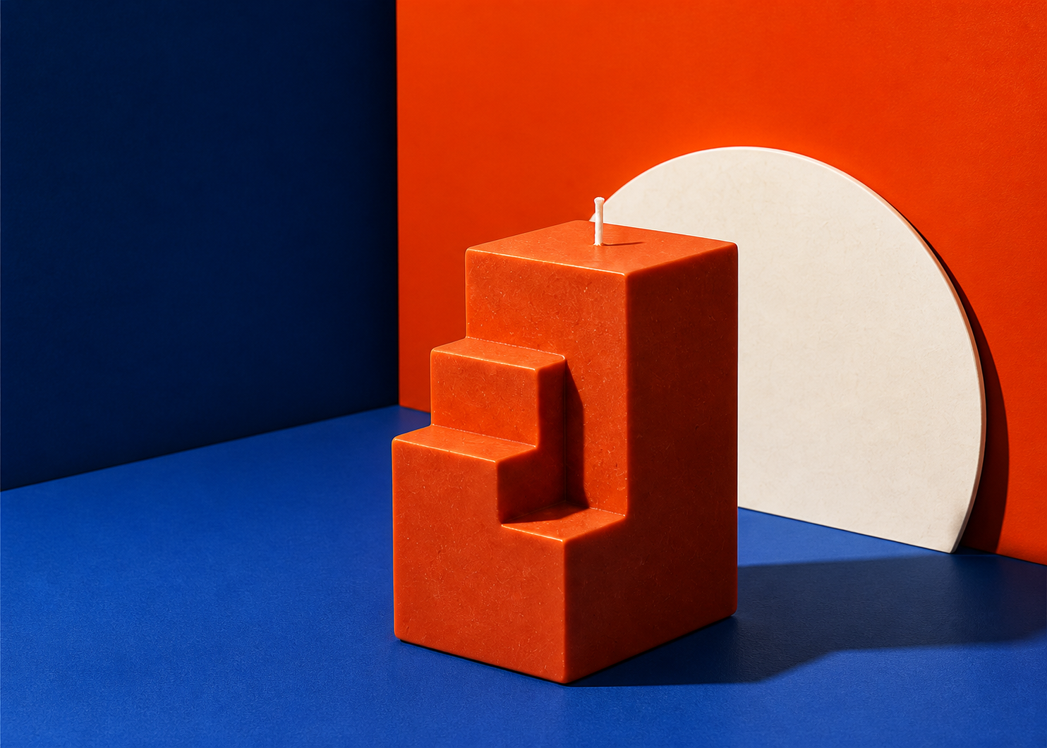 Sculptural orange ZVLZBE candle arranged in a bold cobalt and orange studio set
